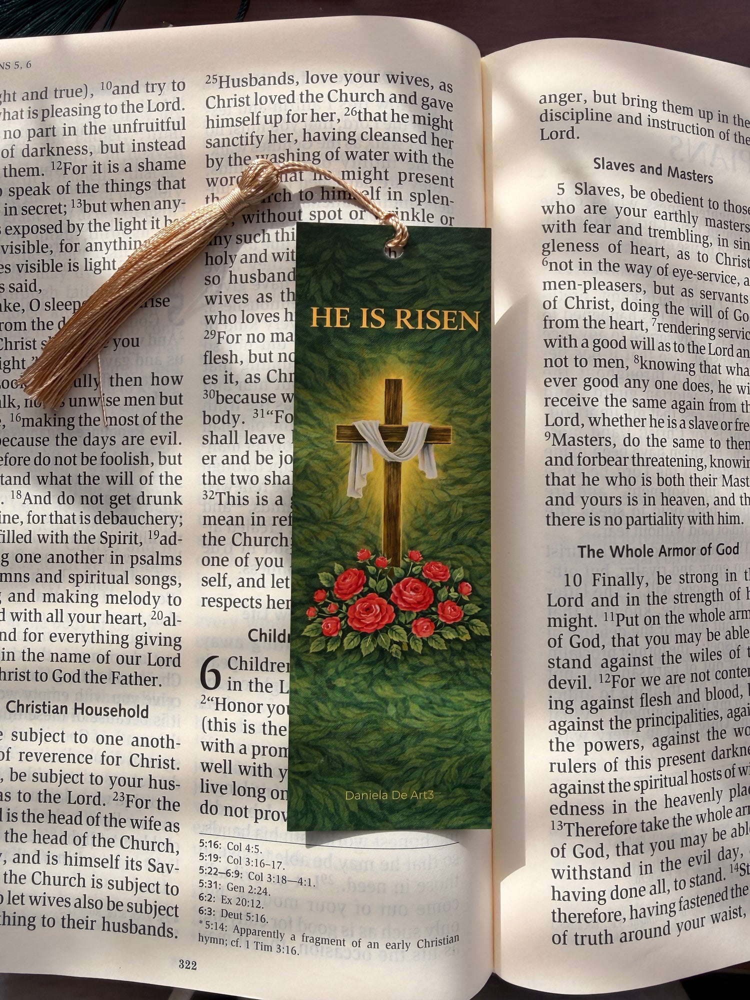 Open book with a 'He is Risen' bookmark featuring a cross and roses on a dark background.